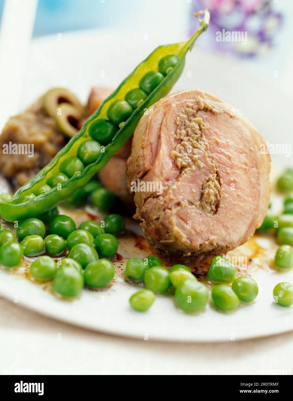 Rotolo di agnello con pasta d'oliva verde e piselli freschi Foto Stock