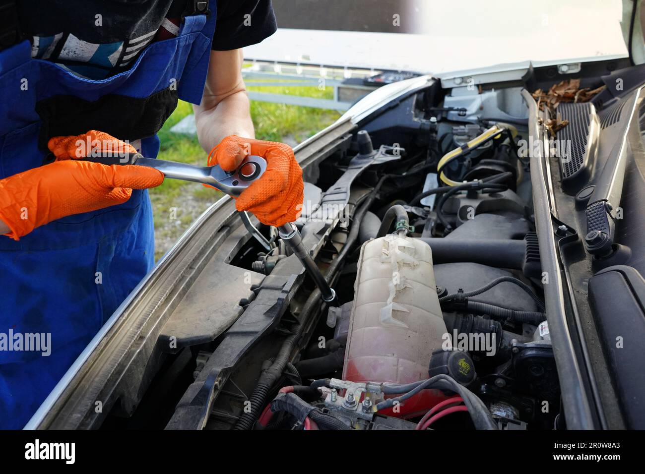 Meccanico che ripara un motore di automobile. Uomo che fissa l'auto rotta. Cambio dell'olio nella vettura. Cambio dell'olio per auto. Foto Stock