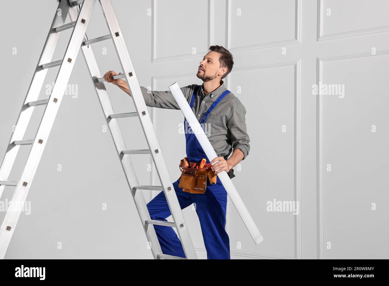 Elettricista in uniforme con lampada da soffitto su scala metallica per  interni Foto stock - Alamy
