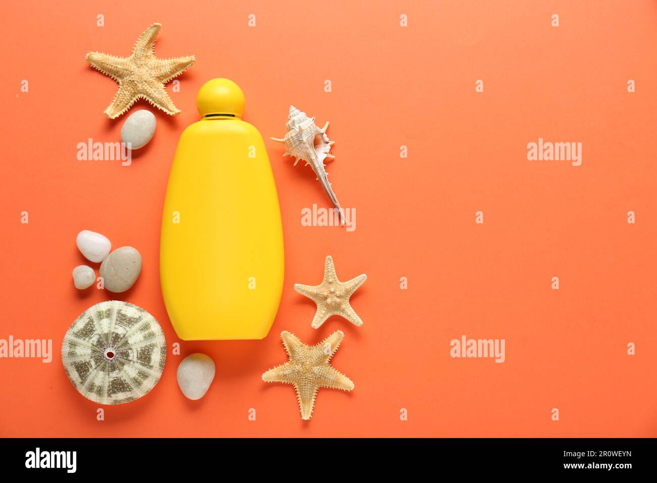 Bottiglia di crema solare e conchiglie su fondo arancione, piatto. Spazio per il testo Foto Stock