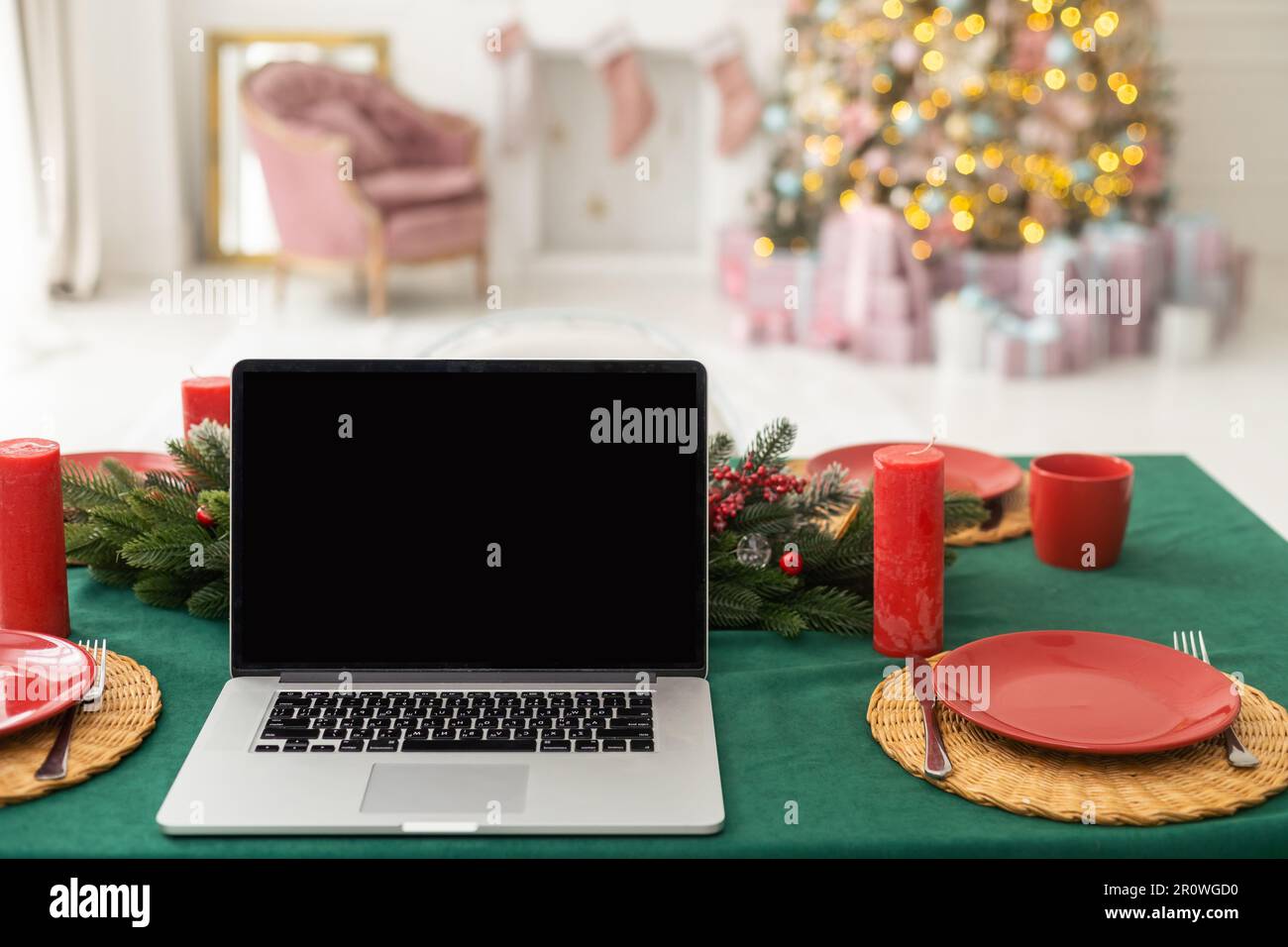 Festeggiamo il buon natale e il nuovo anno a casa, candele e ghirlande, un bicchiere di champagne e un computer portatile sul tavolo in cucina Foto Stock