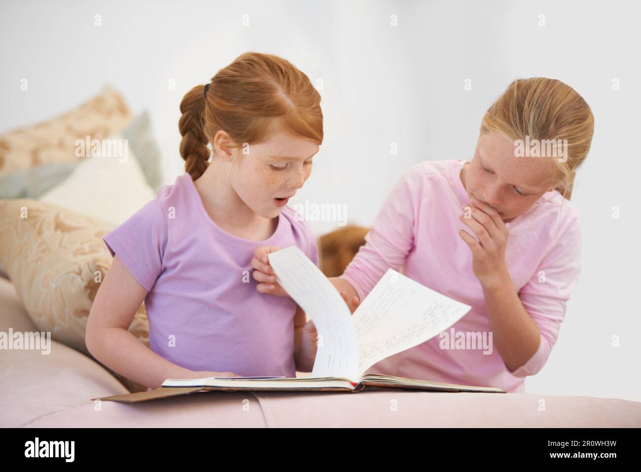 Leggendo a sua sorella. Due sorelle che leggono un libro di storia nel salone. Foto Stock
