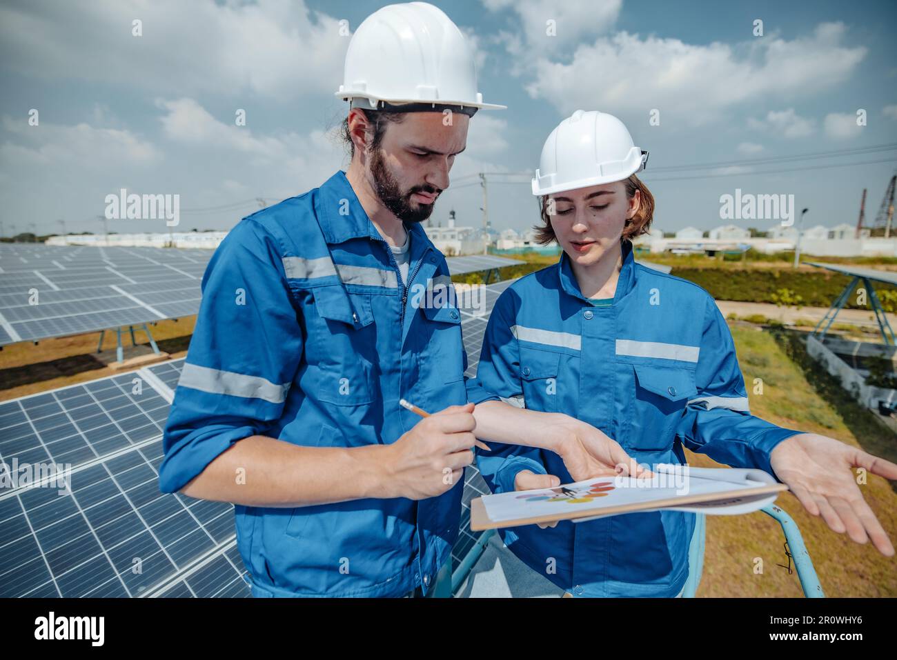 Gli ingegneri dell'energia solare esaminano visivamente gli array di pannelli nei siti agricoli utilizzando progetti e disegni per garantire che l'allineamento, la superficie, l'accesso alla luce solare e. Foto Stock