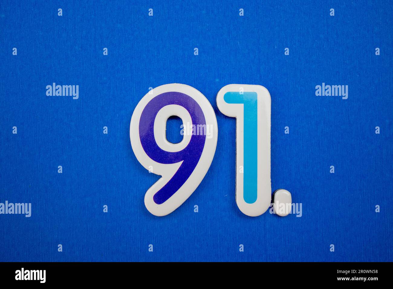 Il numero 91 di colore azzurro, fotografato dall'alto, posto su uno sfondo blu. Foto Stock