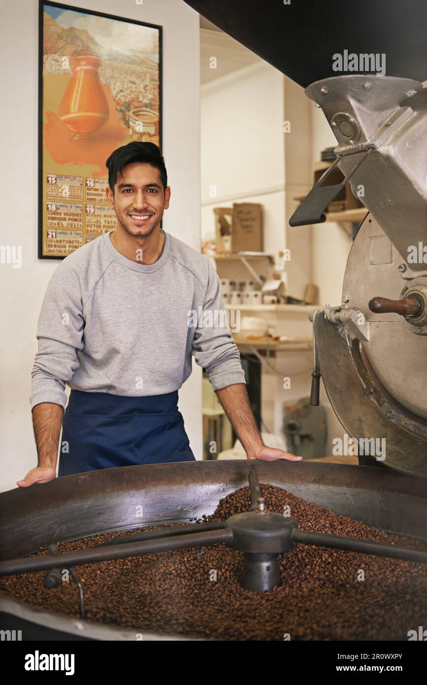 Uso solo i fagioli più fini. Ritratto corto di un giovane che macina e torrefa i chicchi di caffè. Foto Stock
