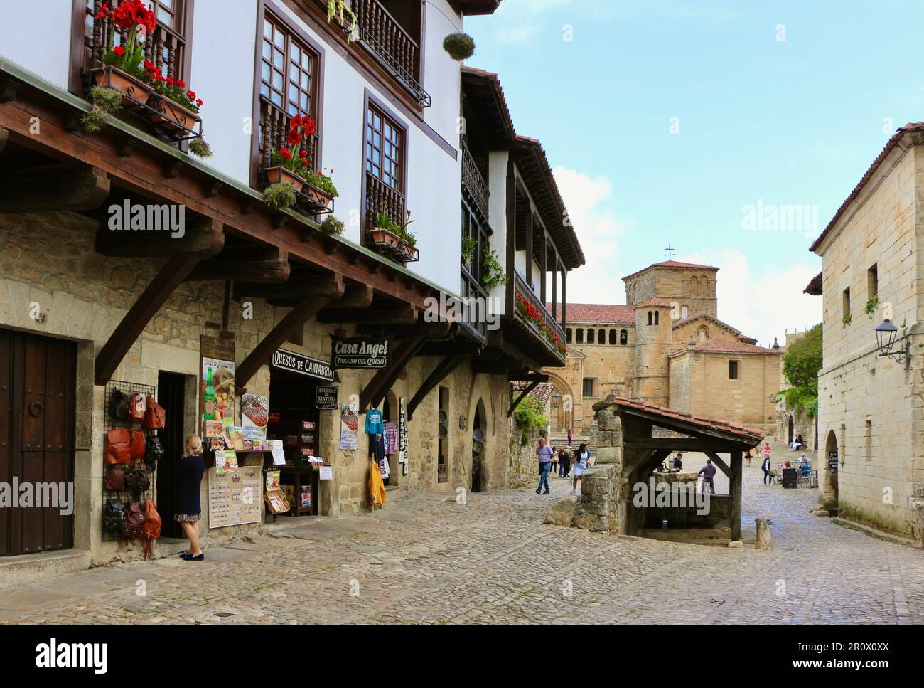 Street view e turisti con l'architettura romanica 12th ° secolo Chiesa della Colegiata in lontananza Santillana del Mar Cantabria Spagna Foto Stock