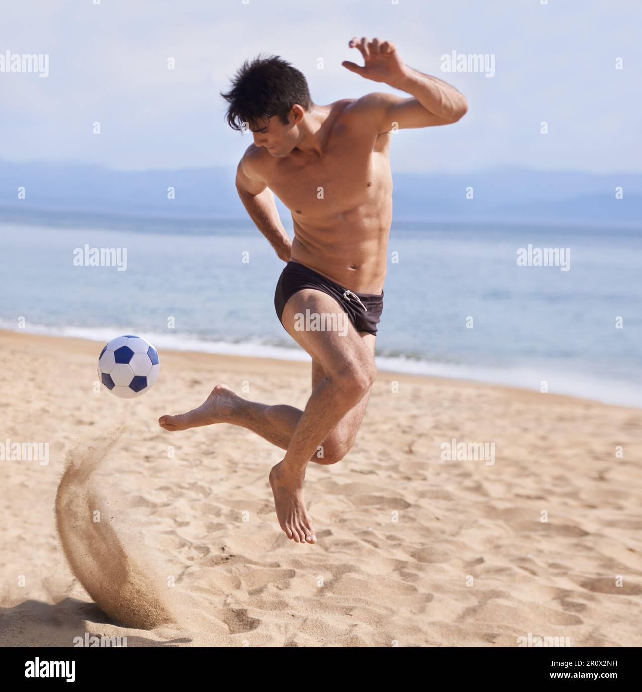 Il mio genere di Beach ball. Un bel giovane che gioca a calcio sulla spiaggia. Foto Stock