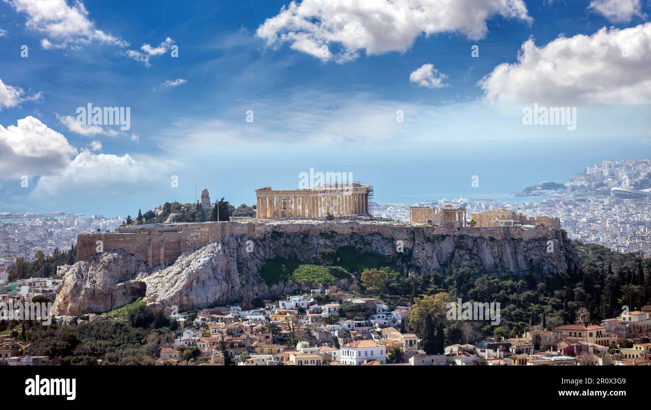 Atene, Grecia. Pietra miliare dell'Acropoli e del tempio del Partenone. Resti antichi, vista aerea dal Colle Lycabettus. Paesaggio urbano, mare blu e cielo nuvoloso b Foto Stock