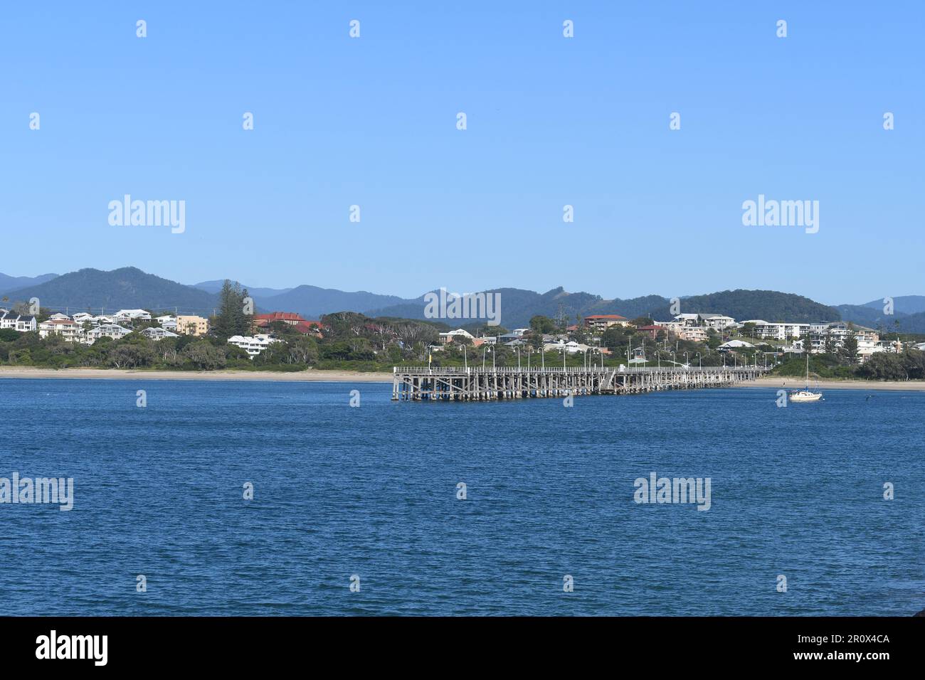 Coffs porto una perfetta spiaggia di mare australiana e destinazione di vacanza. Acqua di mare blu, molo, spiaggia, alberghi e colline sullo sfondo. Foto Stock