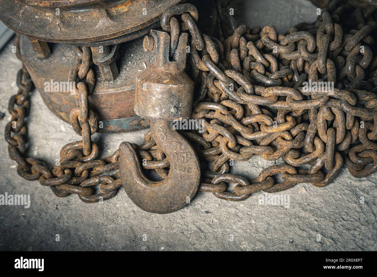 un vecchio paranco a catena in ferro con catena. un grande gancio per il sollevamento dei carichi Foto Stock