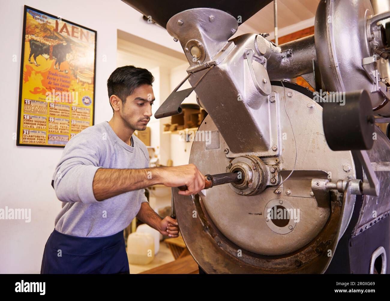 Perfezionare il suo processo di tostatura. una macchina per macinare e tostare i chicchi di caffè. Foto Stock