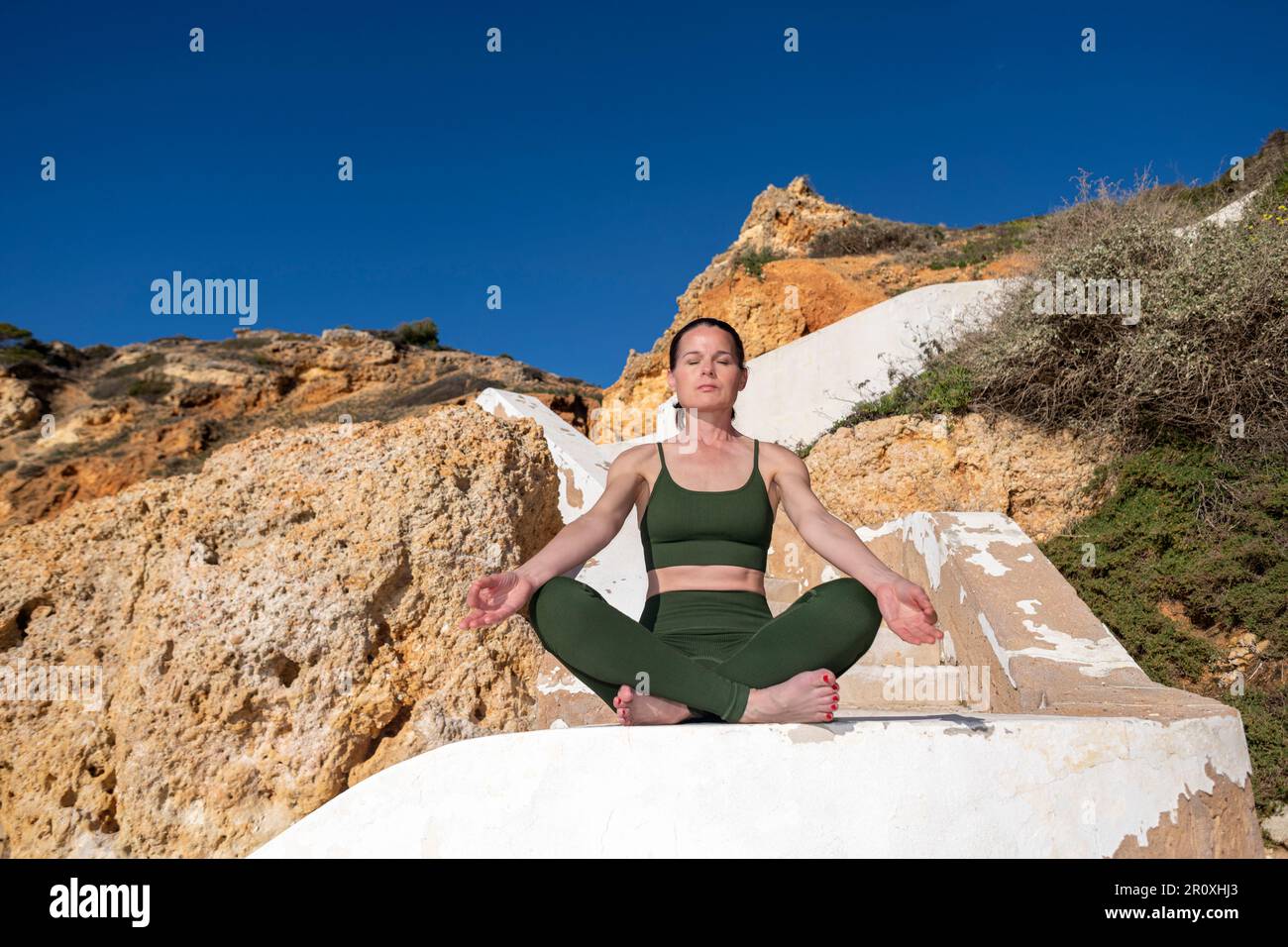 Donna che medita e pratica yoga fuori, Algarve, Portogallo. Foto Stock