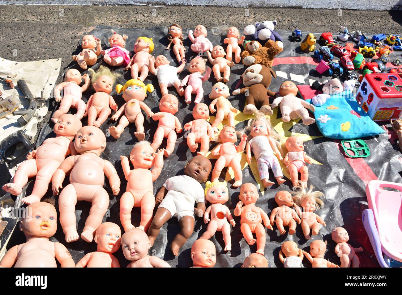 Bambole giocattolo messe in vendita in mostra in una fiera libera con vari altri giocattoli Foto Stock