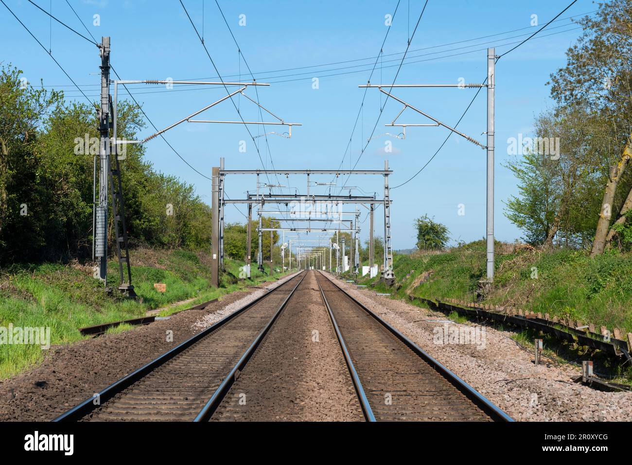 Lungo tratto diritto della linea ferroviaria Greater Anglia da Liverpool Street, passando Margaretting, Essex, UK. Percorso elettrificato Foto Stock