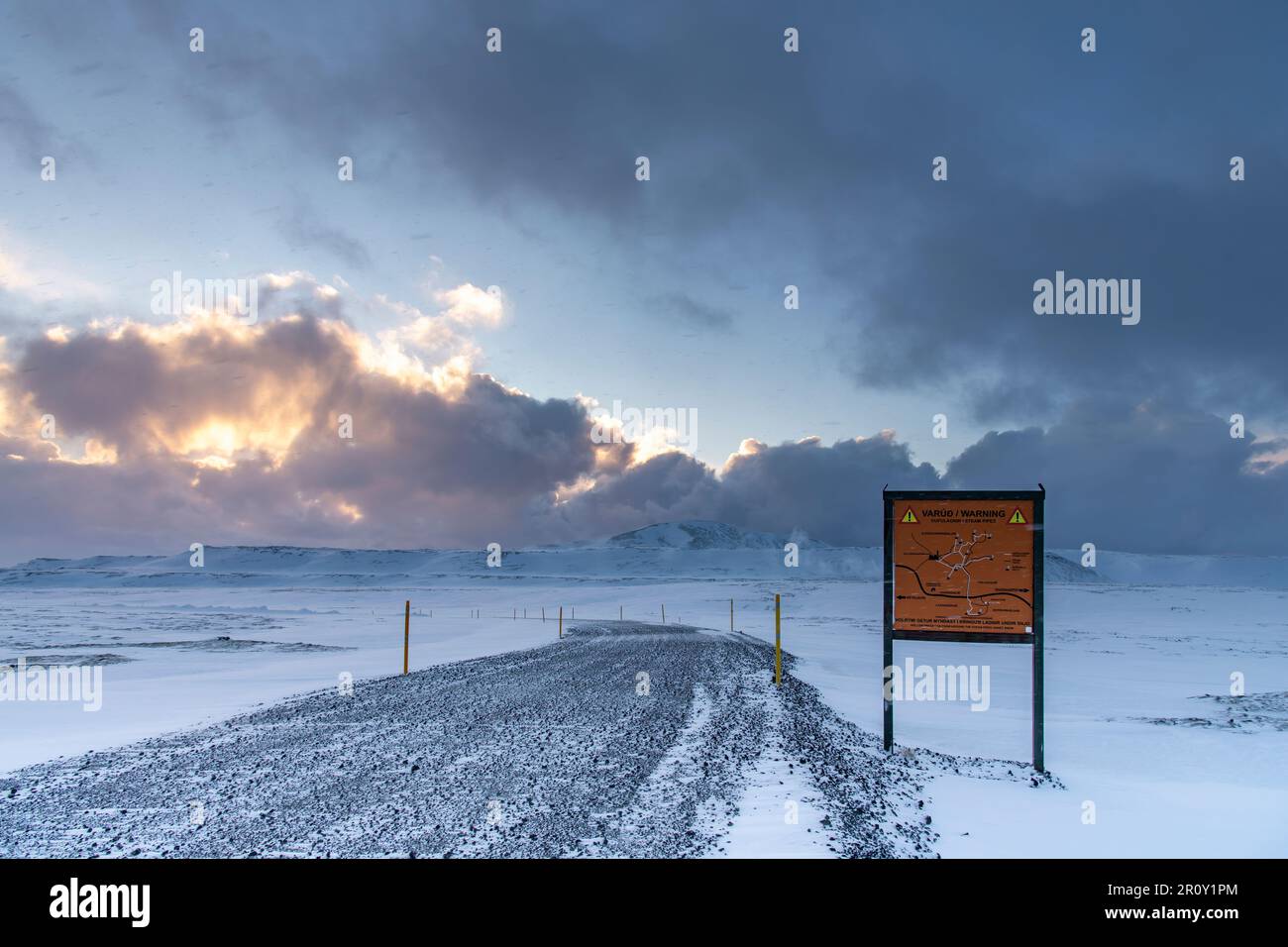 Vista panoramica su un paesaggio innevato in Islanda con strada sterrata e cartello segnaletico in islandese (traduzione in inglese sul cartello) Foto Stock