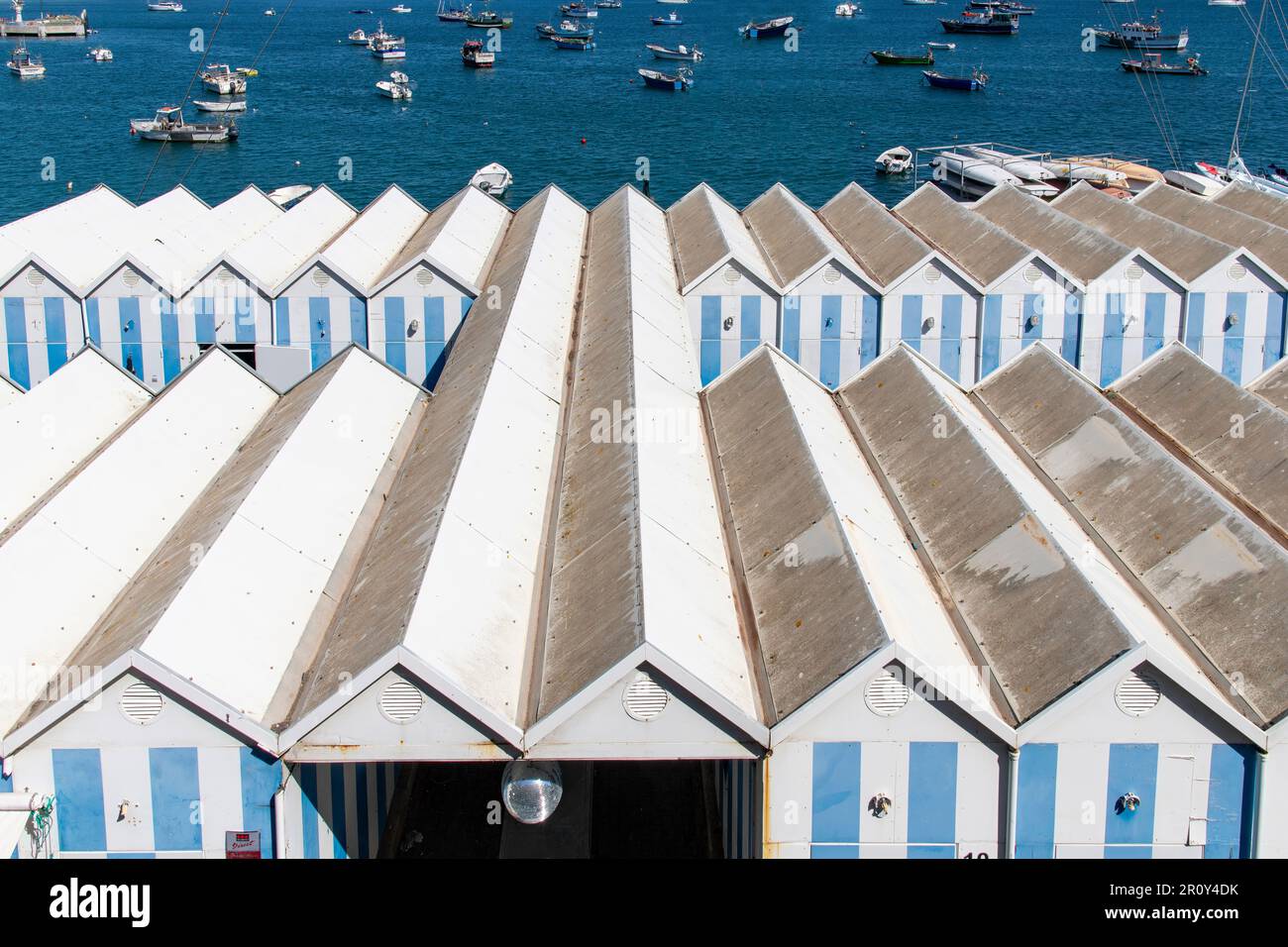 Cascais, Portogallo-Ottobre 2022; Vista ad angolo alta su capannoni di legno, strisce bianche e blu sul molo nel porto della città Foto Stock