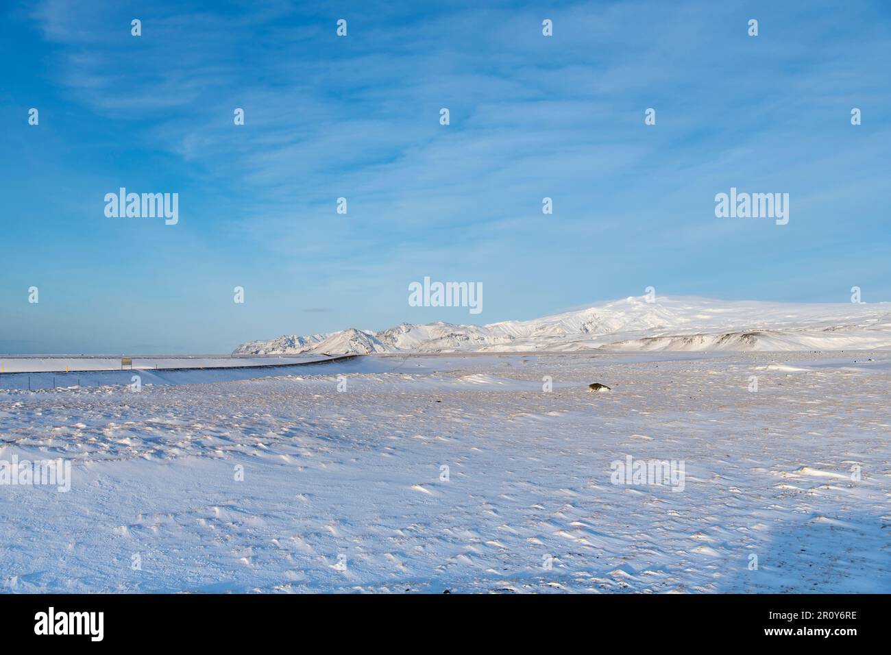 Vista sul paesaggio vulcanico piatto innevato con montagne sullo sfondo vicino al ghiacciaio Eyjafjallajokull e al vulcano nell'agai meridionale dell'Islanda Foto Stock