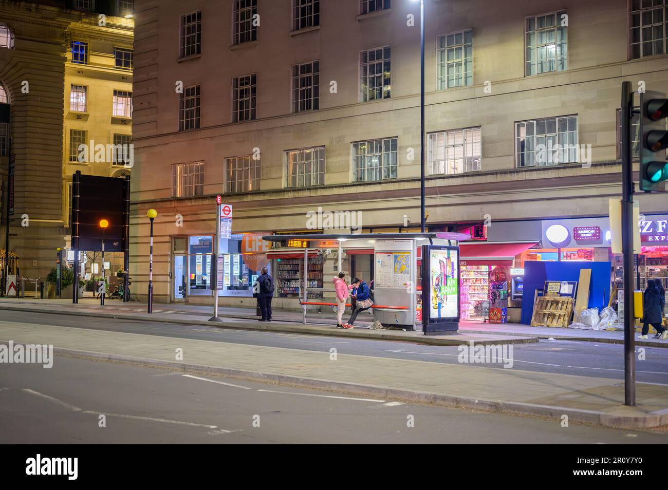 LONDRA - 21 aprile 2023: Vista notturna delle persone in attesa alla fermata dell'autobus fuori dalla County Hall a Southbank, Londra, alla fine del Westminster Bridge. Foto Stock