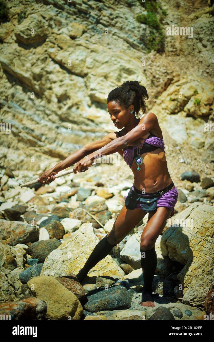 Bella donna nera in abiti viola arenata su un'isola deserta Foto Stock