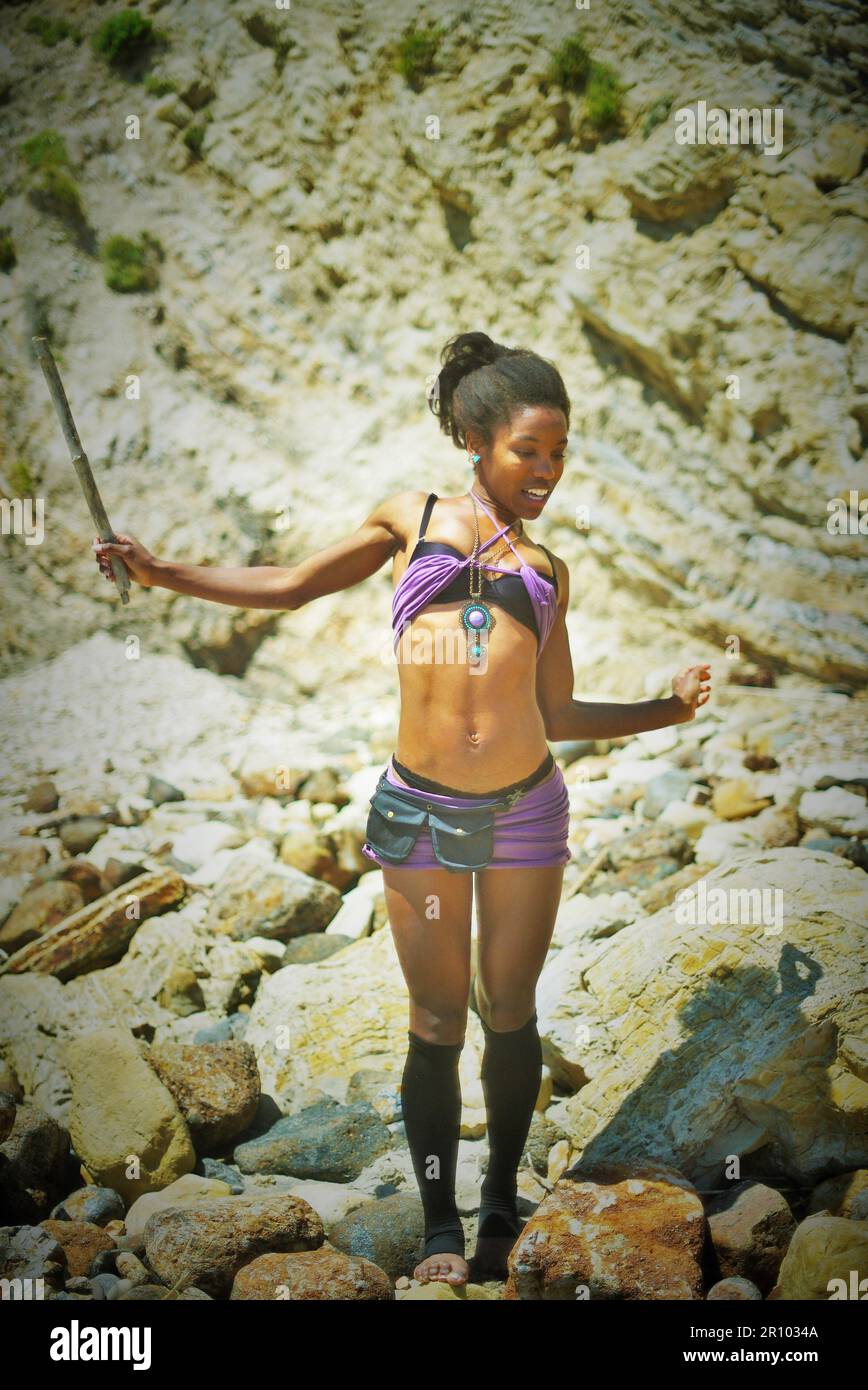 Bella donna nera in abiti viola arenata su un'isola deserta Foto Stock