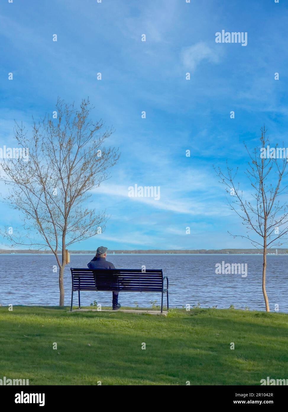 Un uomo di mezza età seduto sul lungomare e guardando avanti Foto Stock