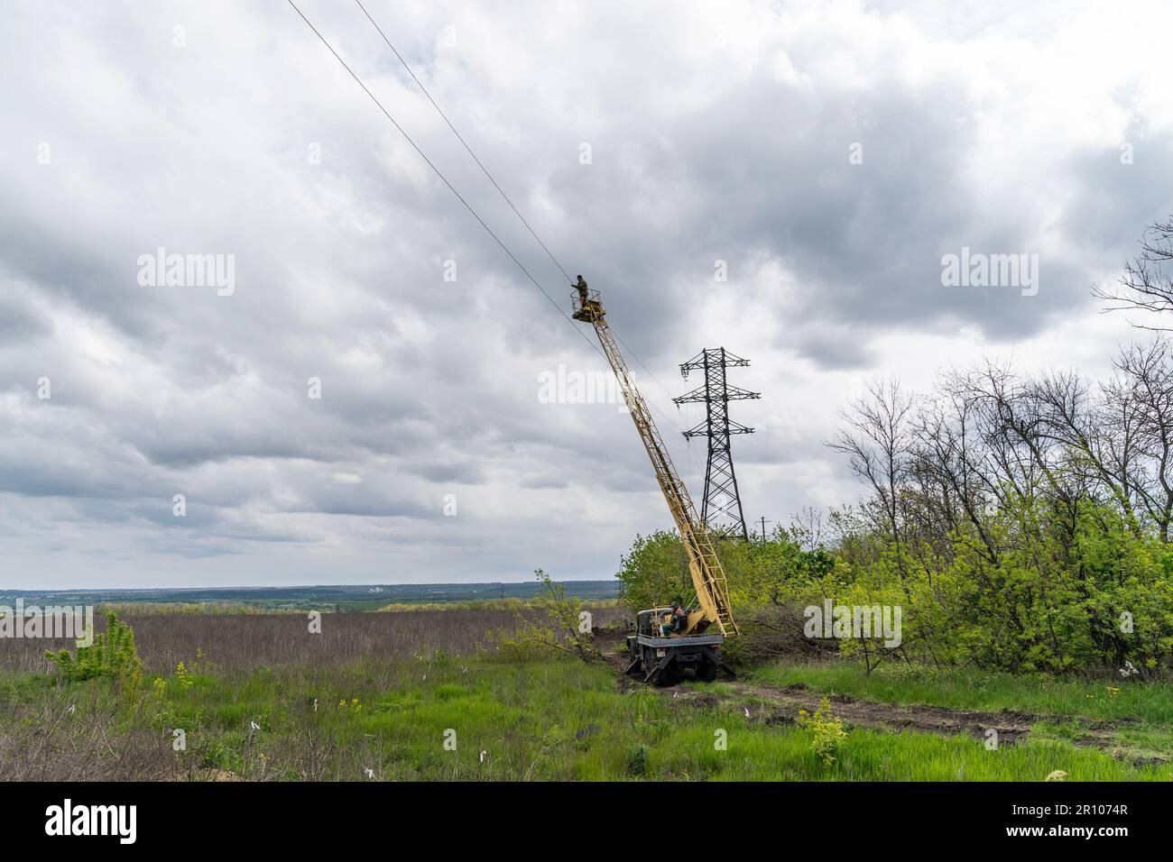 Lavoratori che riparano la linea di trasmissione di energia elettrica distrutta durante l'invasione russa vicino al villaggio di Kamyanka della regione di Kharkiv in Ucraina il 10 maggio 2023 Foto Stock