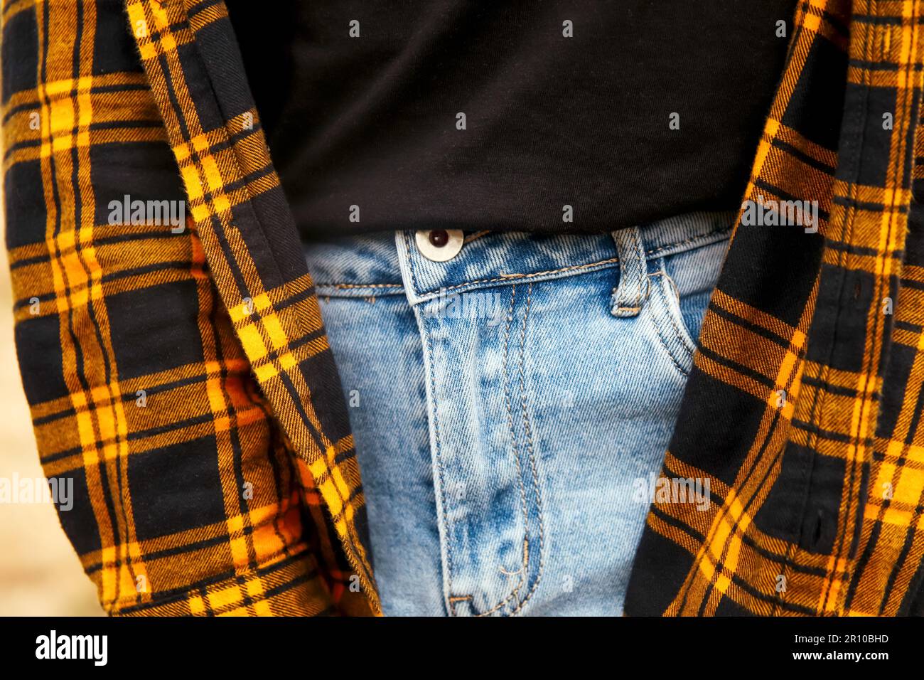 Hippster stile donna. Maglia a quadri millennial gialla e nera a scacchi. Design. Stile di vita alla moda. Abbigliamento casual. Denim blu Foto Stock