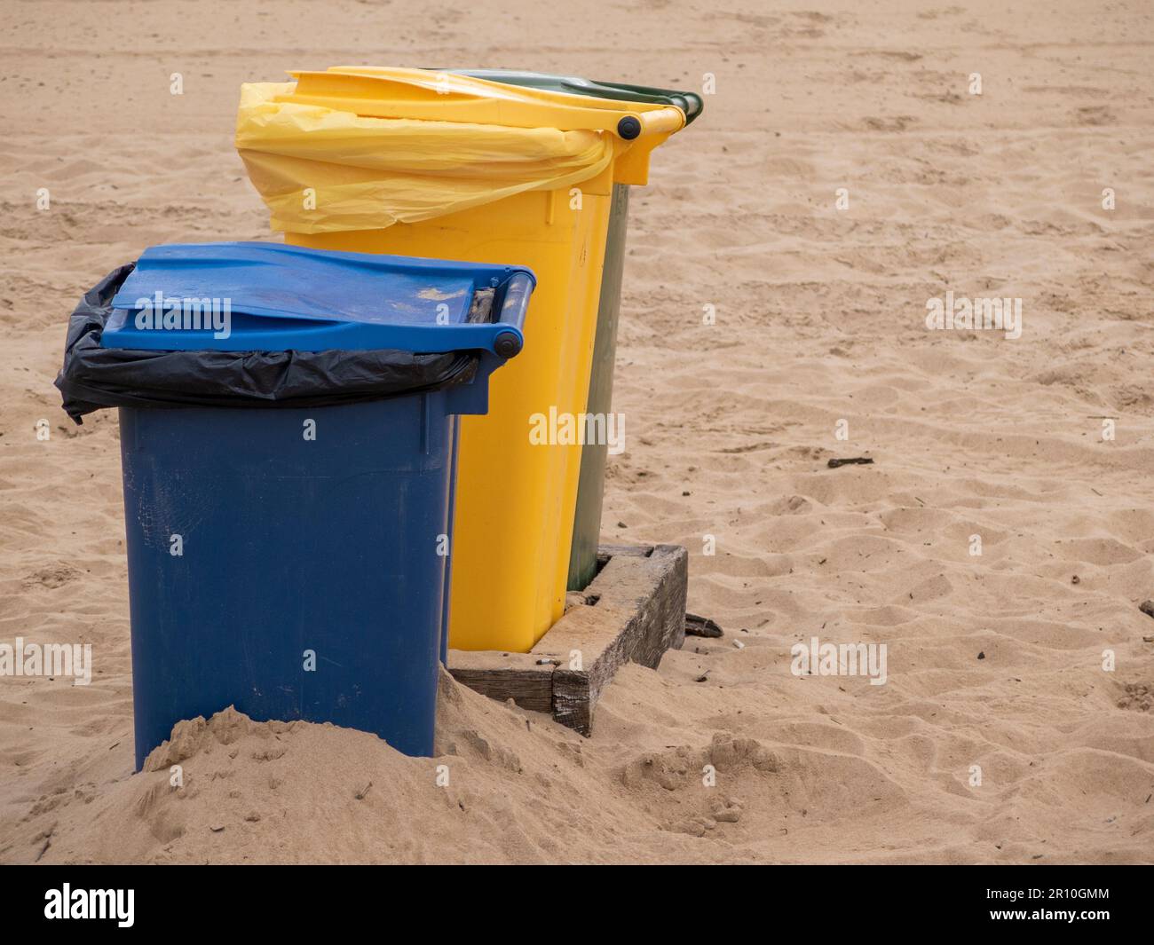 Spiagge pulite e sostenibili: Importanza dei colorati contenitori per il riciclaggio Foto Stock