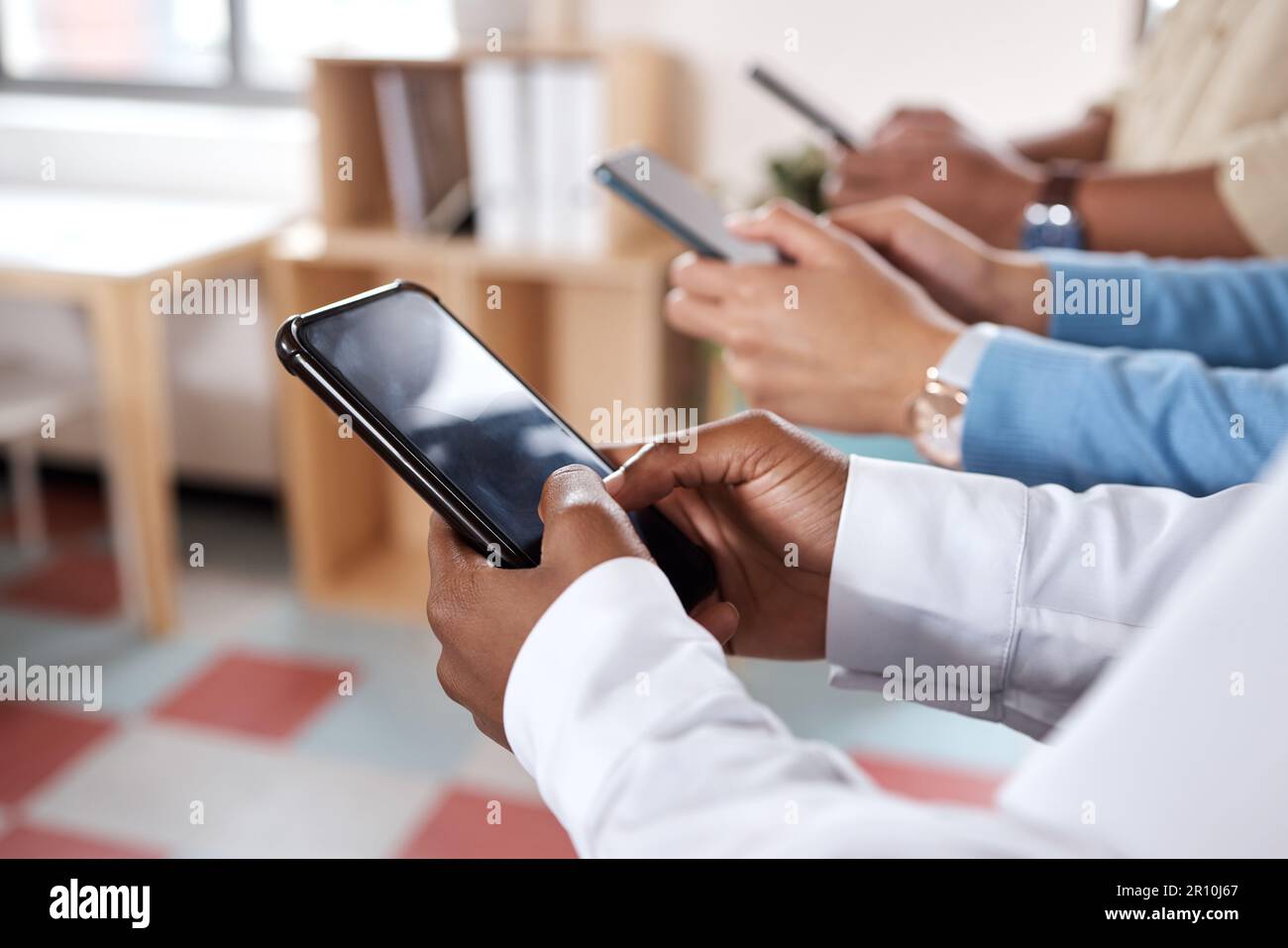 I dispositivi sono sempre pronti. un gruppo di uomini d'affari irriconoscibili che utilizzano il proprio smartphone in un ufficio moderno. Foto Stock