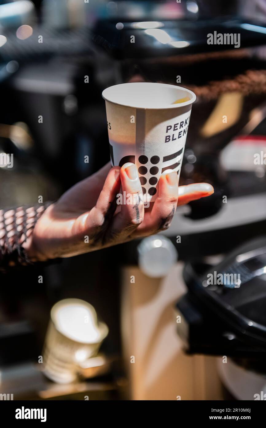 Elegante mano e dita tatuate di una mano da donna che tiene una tazza di caffè Foto Stock