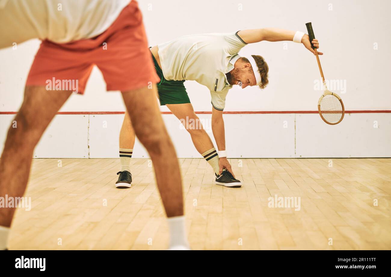 Quale modo migliore per mantenersi in forma che con lo squash. due giovani uomini che si allungano prima di giocare una partita di squash. Foto Stock