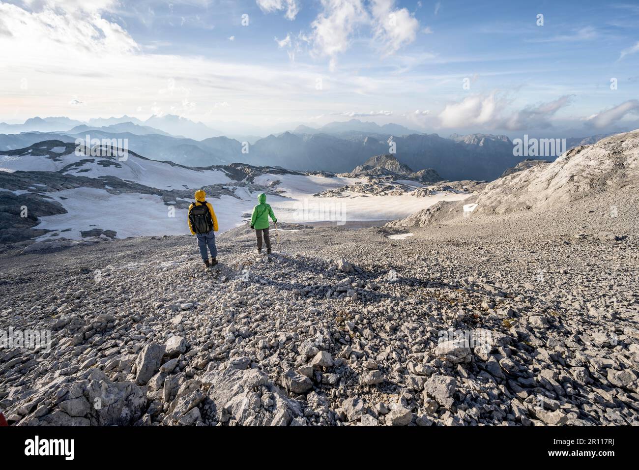 Vista dell'altopiano roccioso con ghiacciaio e resti di neve, l'Alpe di Uebergossene, gli alpinisti in cima alle Alpi di Hochkoenig e Berchtesgaden Foto Stock