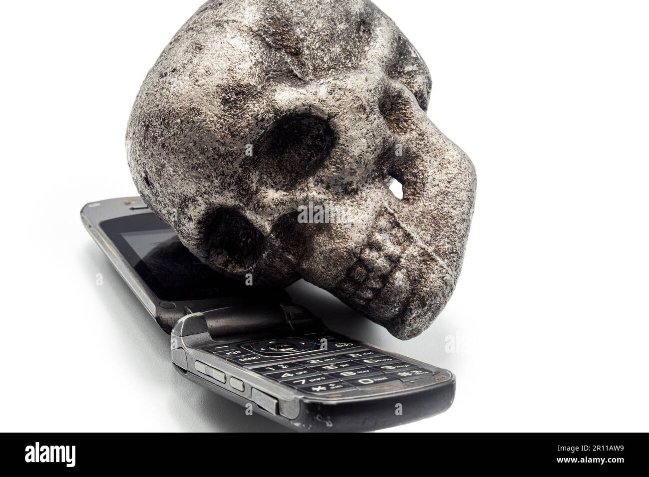 vecchio cellulare e cranio di metallo, parlare al telefono e la guida è pericoloso Foto Stock
