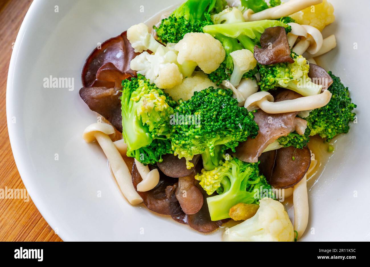 Menu di cibi salutari, funghi fritti in primo piano, cavolfiore e broccoli, cibo di verdure misto tailandese sano su un piatto bianco. Immagine ravvicinata, vista fr Foto Stock
