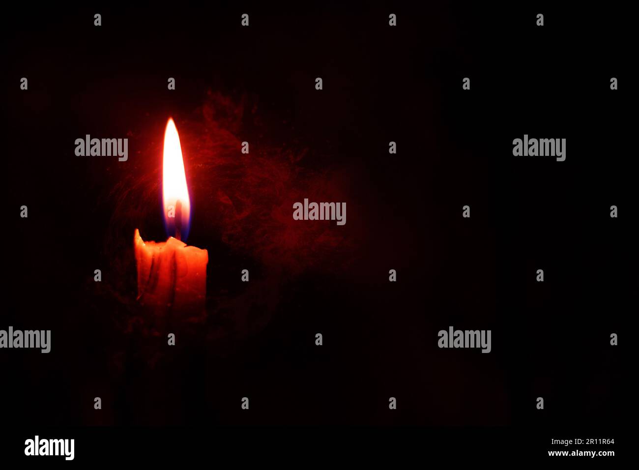 una fiamma a candela al buio come sfondo Foto Stock