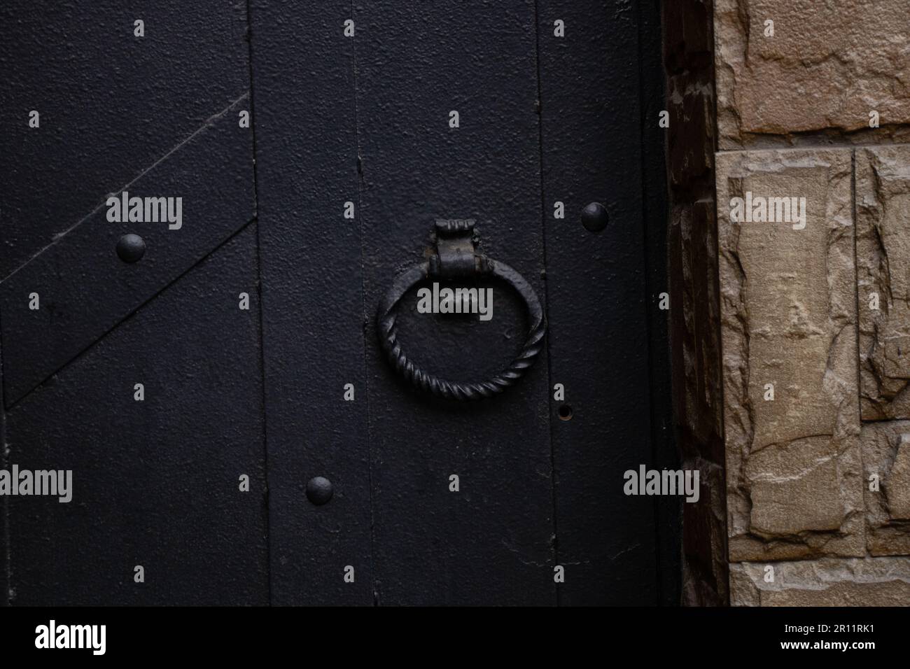 maniglia forgiata rotonda su una vecchia porta in ferro nero primo piano Foto Stock