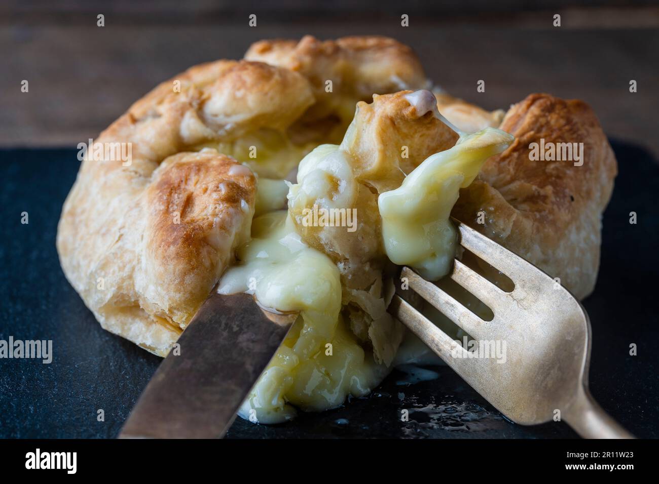 Formaggio Camembert cotto in pasta sfoglia con forchetta e coltello, primo piano Foto Stock