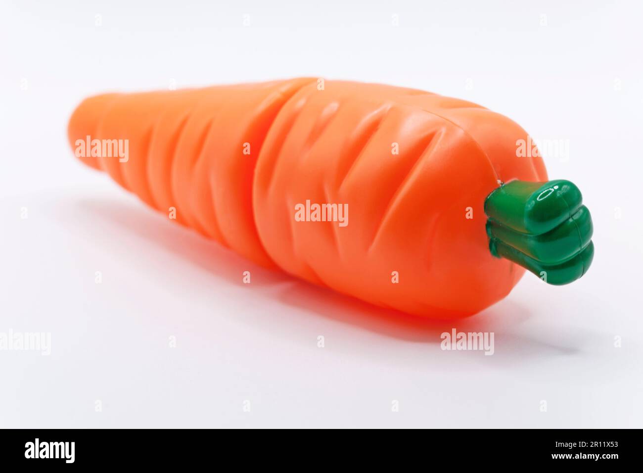 una carota giocattolo su sfondo bianco Foto Stock