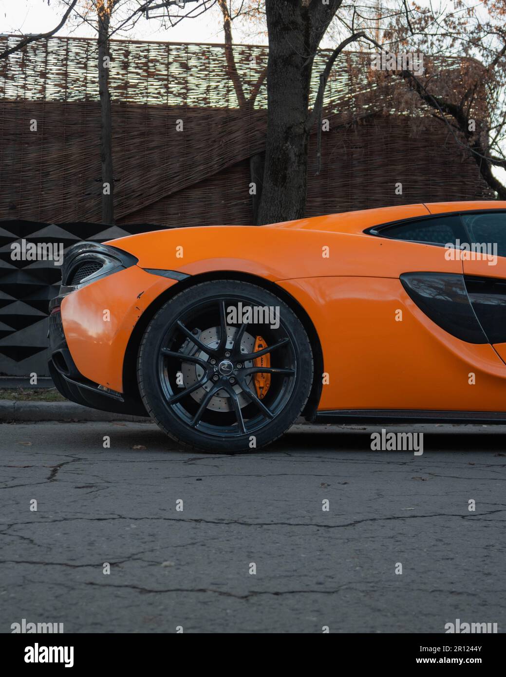 Un'elegante auto sportiva arancione e nera vista alla guida su una strada trafficata della città Foto Stock