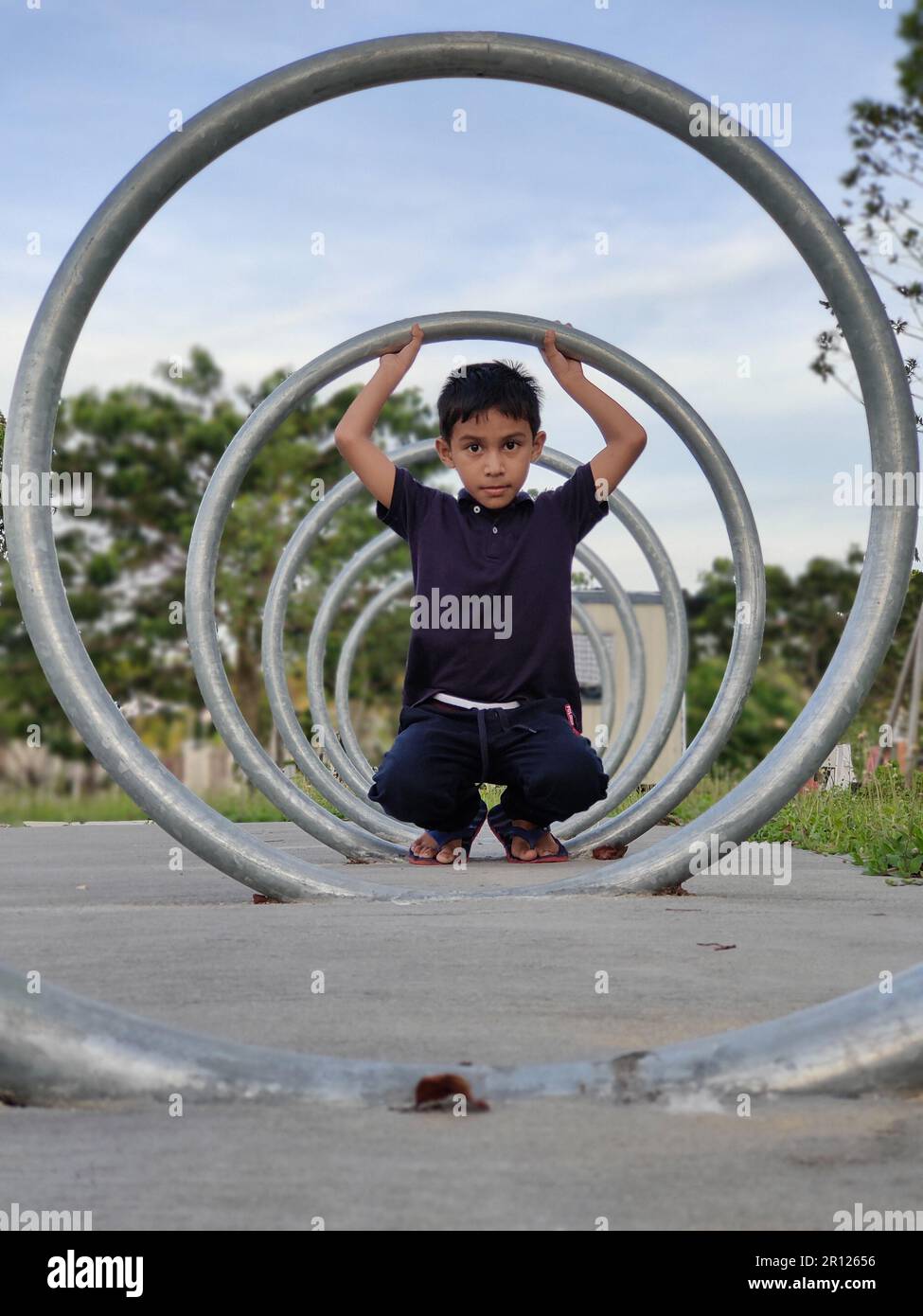 Malesia, 10 maggio 2022: Un ragazzo gioca con un cerchio di ferro. Foto Stock Malesia, 10 maggio 2022: Un ragazzo gioca con un cerchio di ferro. Foto Stock