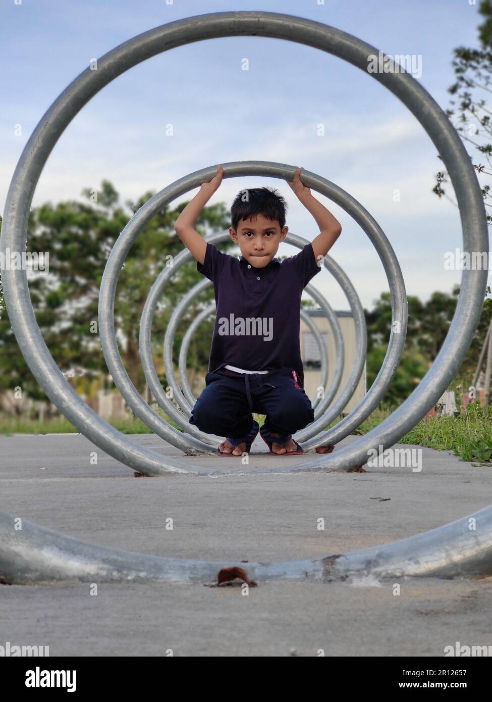Malesia, 10 maggio 2022: Un ragazzo gioca con un cerchio di ferro. Foto Stock Malesia, 10 maggio 2022: Un ragazzo gioca con un cerchio di ferro. Foto Stock