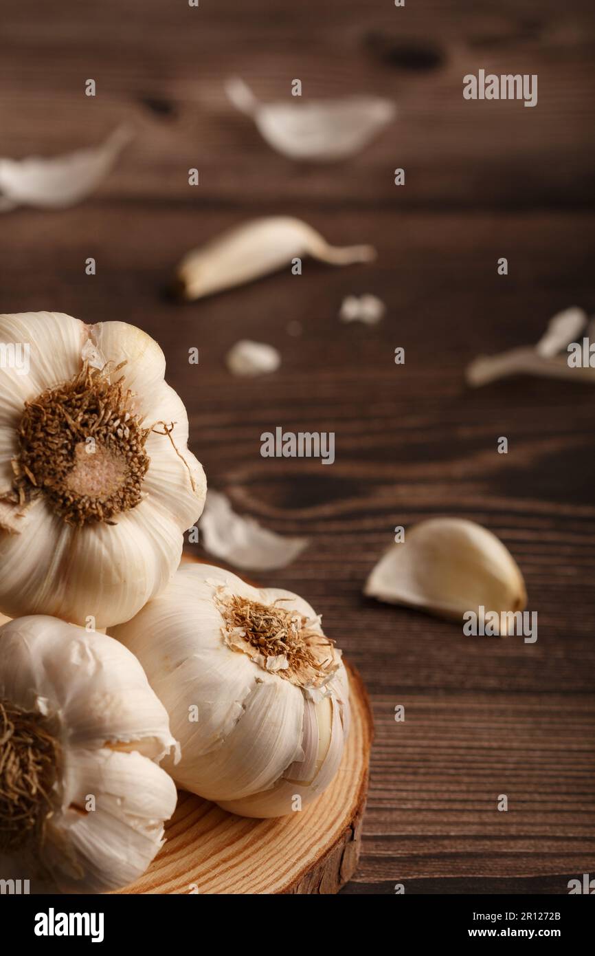 Testa d'aglio con spicchi su una fettina di legno di pino rotondo. Tavolo rustico. Spazio di copia. Primo piano Foto Stock