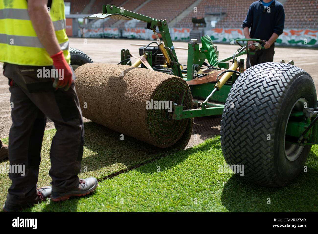 LUBIN, POLONIA - 28 MAGGIO 2021: Due operai che posano erba in un rotolo su un campo di calcio allo stadio Zaglebie Lubin. Foto Stock