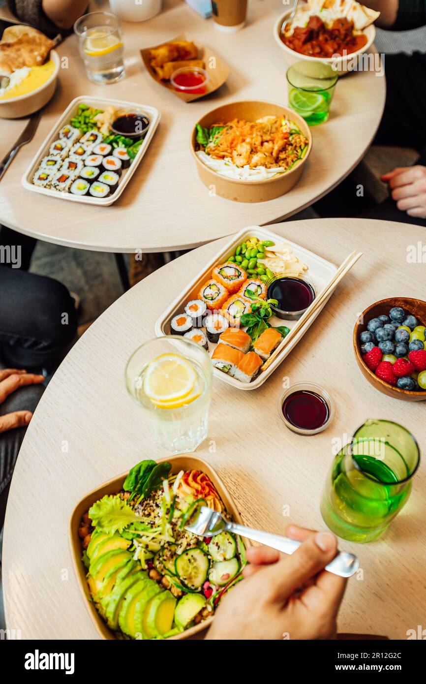 Un gruppo di persone che gustano un pasto insieme a un tavolo, con piatti di cibo delizioso posti davanti a ogni individuo Foto Stock