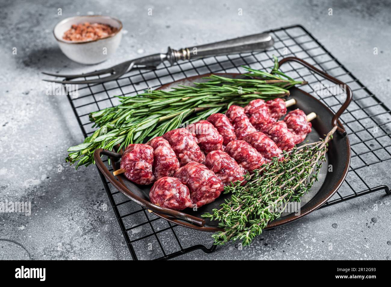 Kebab di Urfa Turco crudo decorato con erbe, spezie e forchetta di carne. Sfondo grigio. Vista dall'alto. Foto Stock