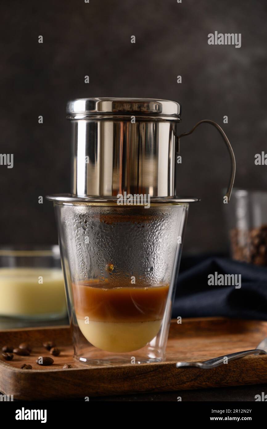 Metodo tradizionale di preparazione del caffè vietnamita con latte condensato su fondo nero. Primo piano. Formato verticale. Foto Stock