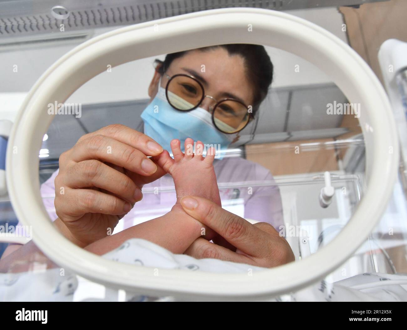 HANDAN, CINA - 11 MAGGIO 2023 - Un'infermiera dà un tocco al piede a un neonato presso il reparto di neonatologia del distretto Yongnian No 1 Hospital a Handan, Nor Foto Stock