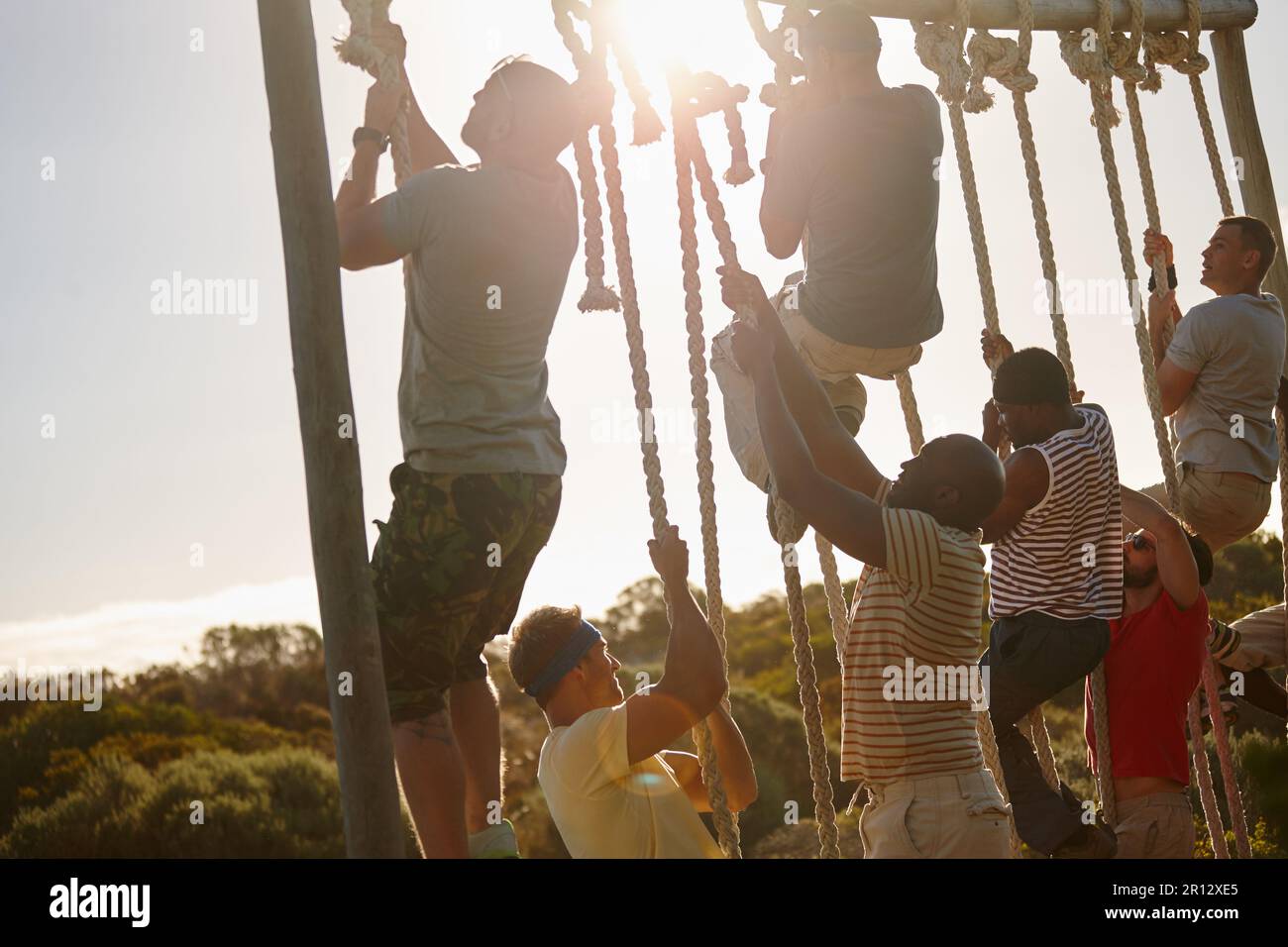 Non fermarsi fino a raggiungere la cima. un gruppo di uomini che si arrampicano sulle corde in un campo militare. Foto Stock