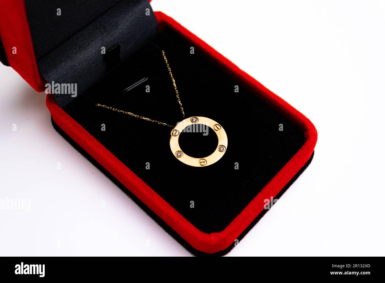 Una collana dorata all'interno di una cassa rossa su sfondo bianco. Foto Stock
