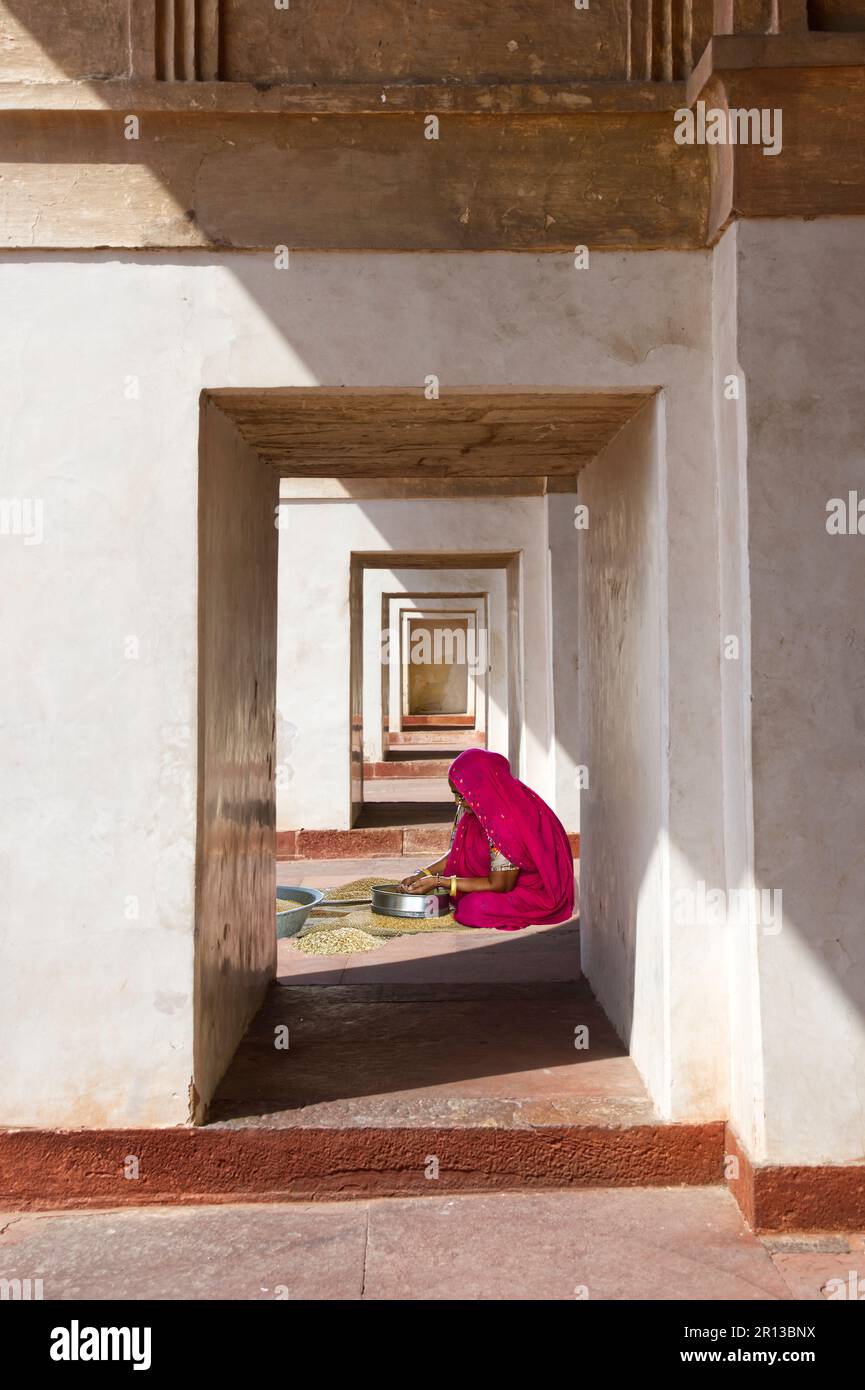 Donna in sari rosa rosso seduta all'aperto e prepara il pasto per la sua famiglia Foto Stock